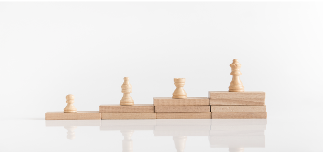 Chess pieces climbing ascending wooden steps